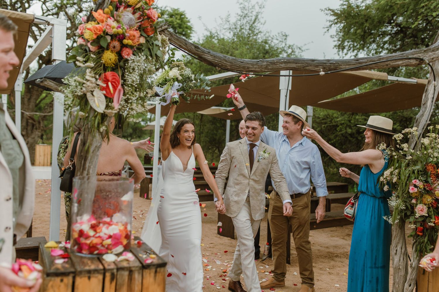Wedding ceremony celebration with guests gathered under decorated trees.