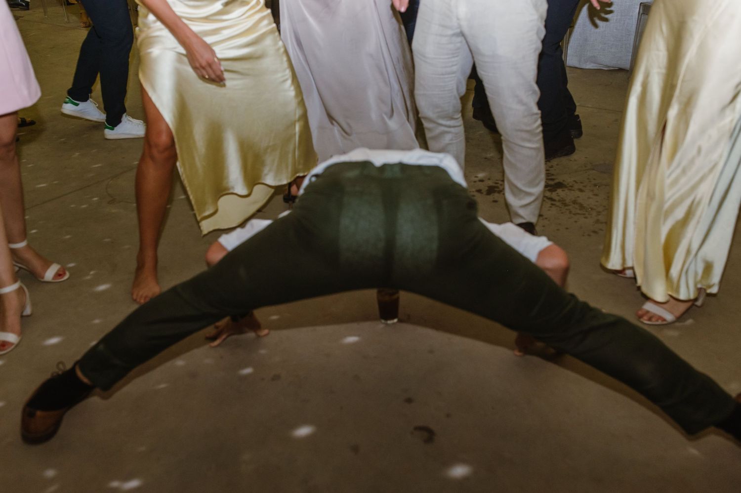 Guests dance and celebrate on a dimly lit dance floor at a wedding reception.