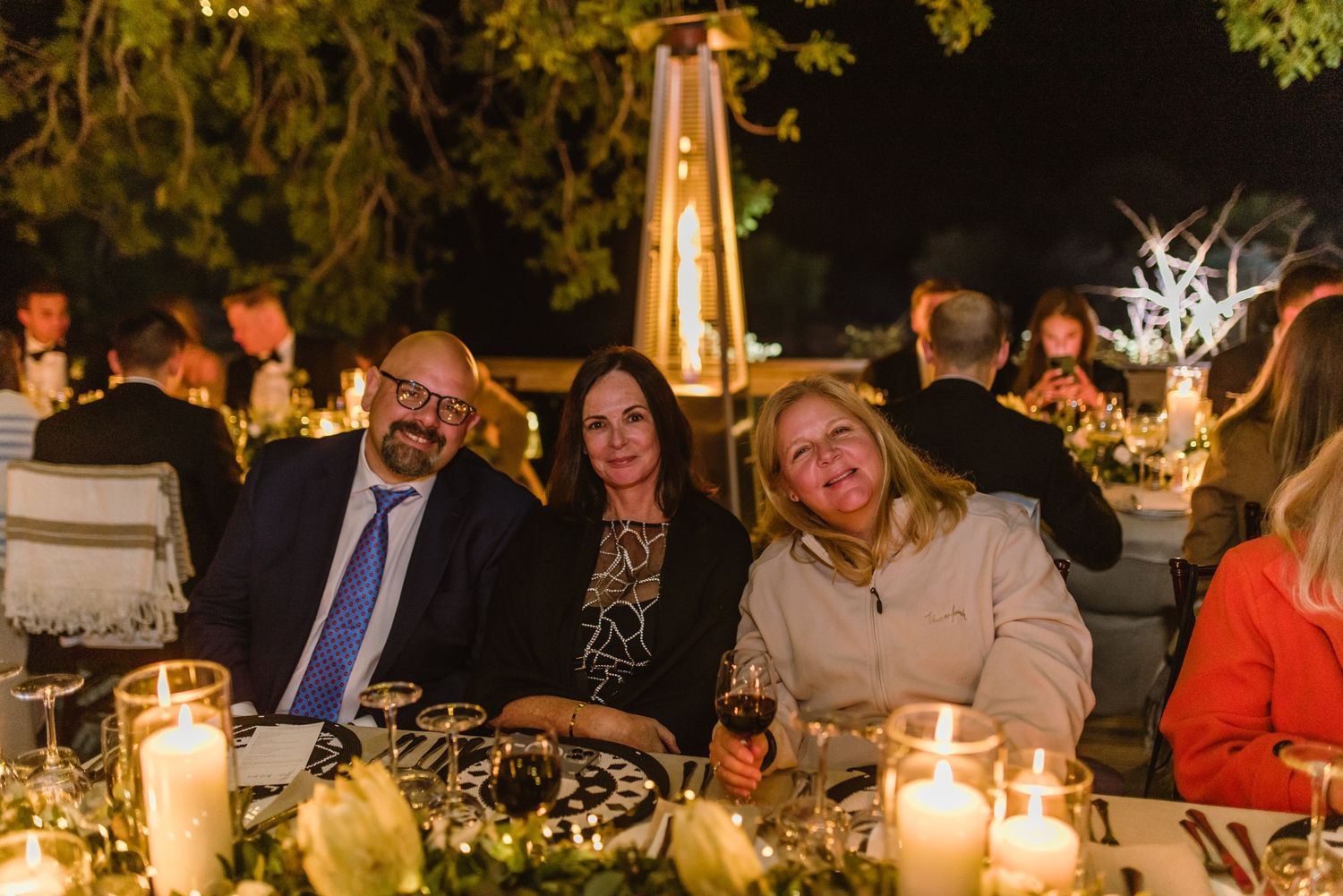 Candlelit outdoor reception tables with guests enjoying the evening atmosphere.
