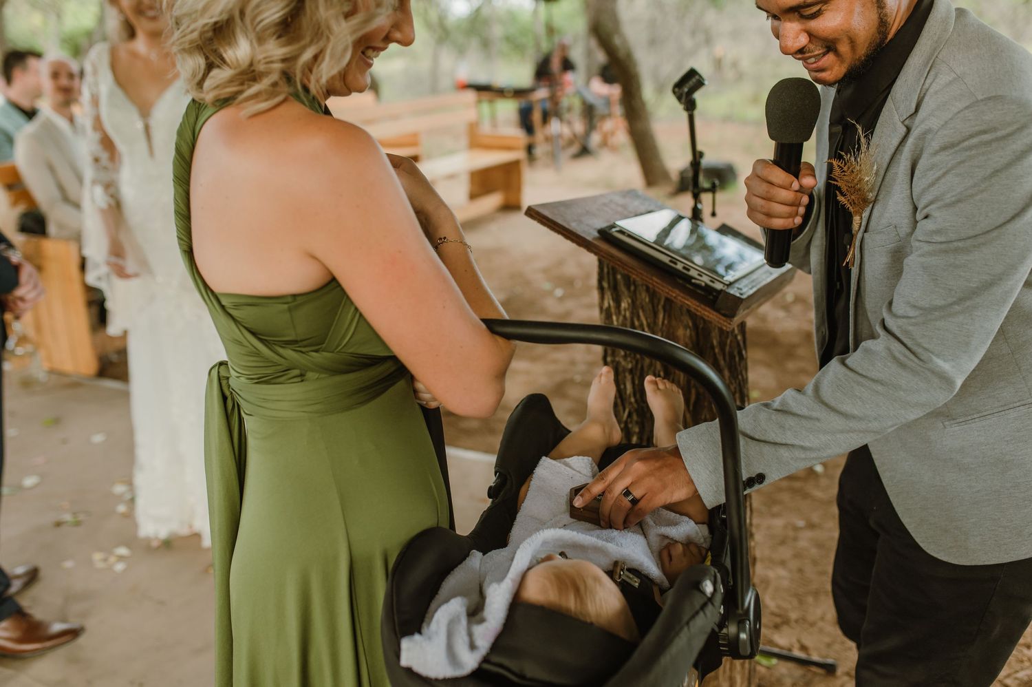 Wedding guest in a green dress signs the marriage certificate at an outdoor ceremony.
