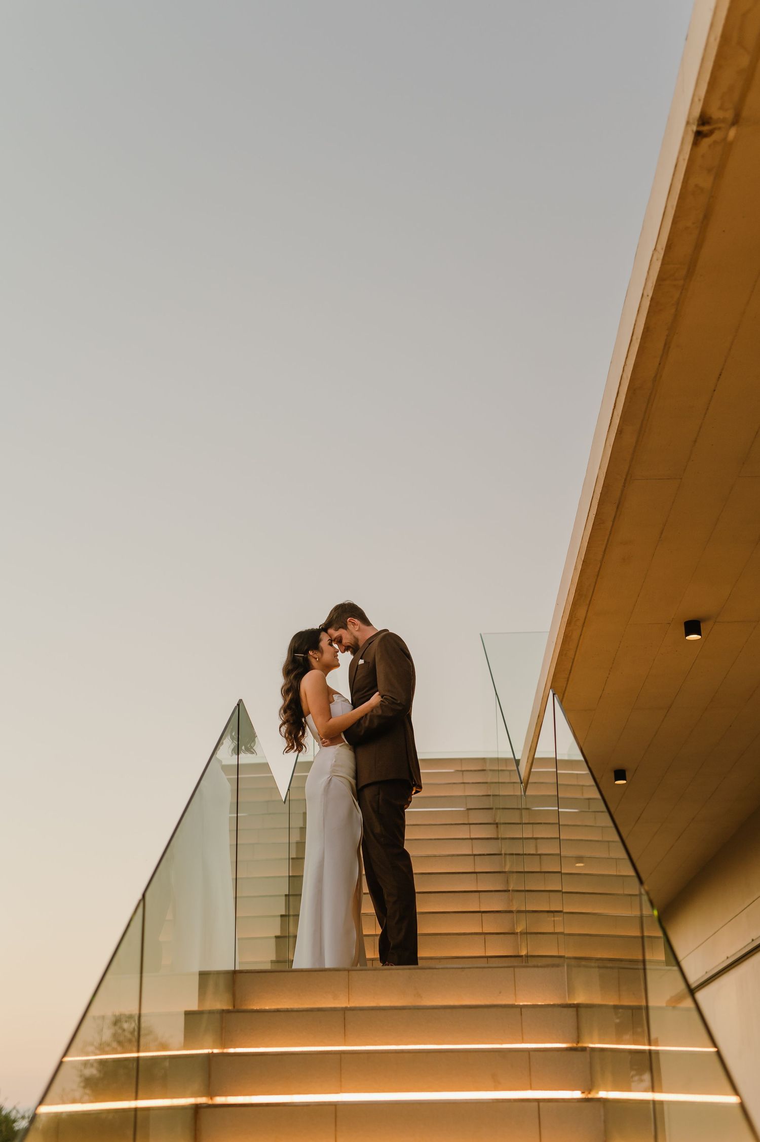 Couple sharing an intimate moment on modern outdoor stairs at sunset.