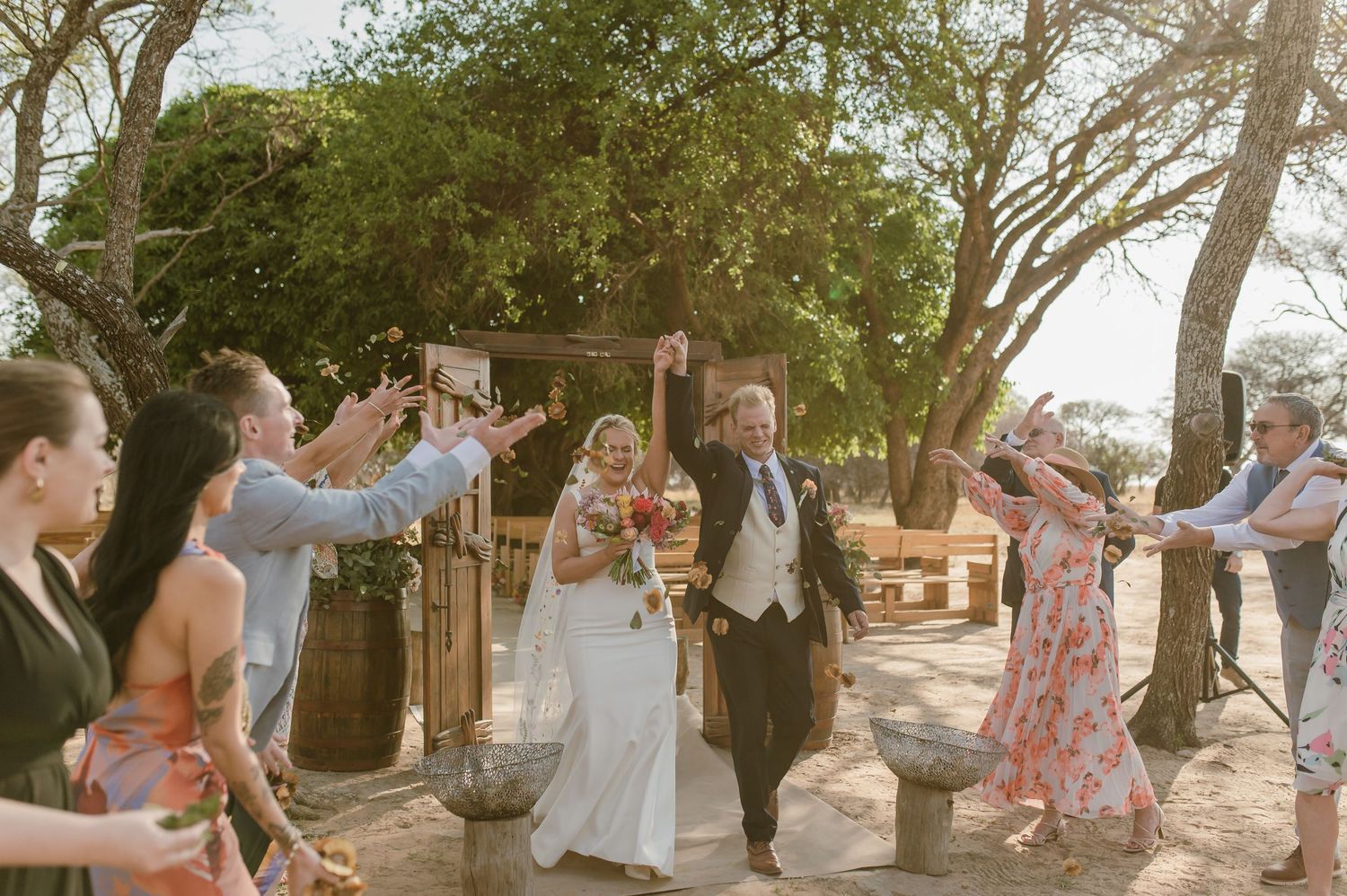 Wedding celebration captured in natural outdoor setting with trees and sunlight.