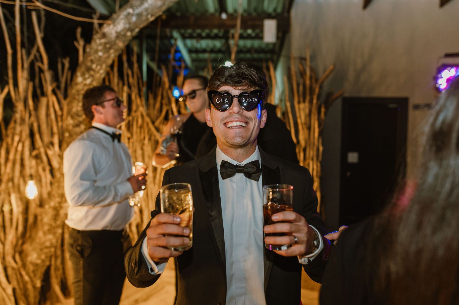 Guests in formal wear raising glasses during an evening wedding celebration.