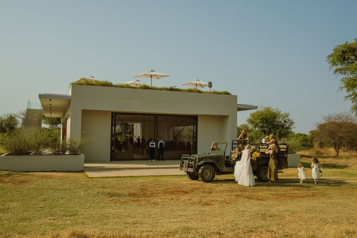 Contemporary white building with guests gathered outside under clear blue skies.