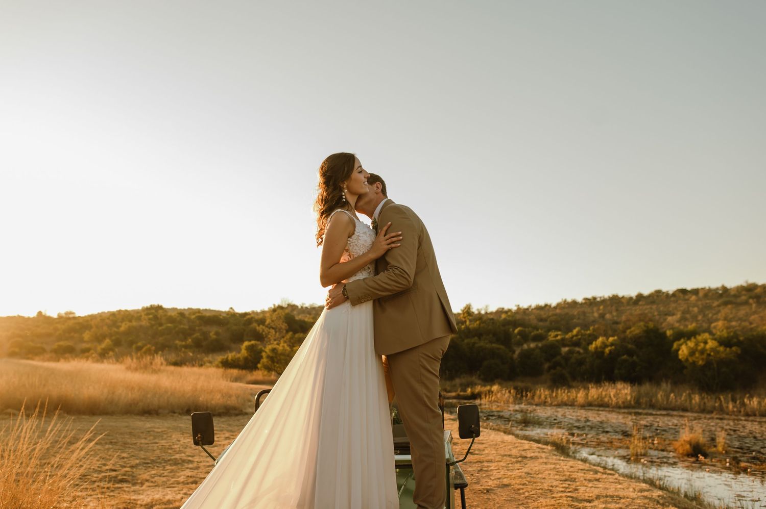 Romantic sunset wedding photoshoot by a scenic lake with golden light.