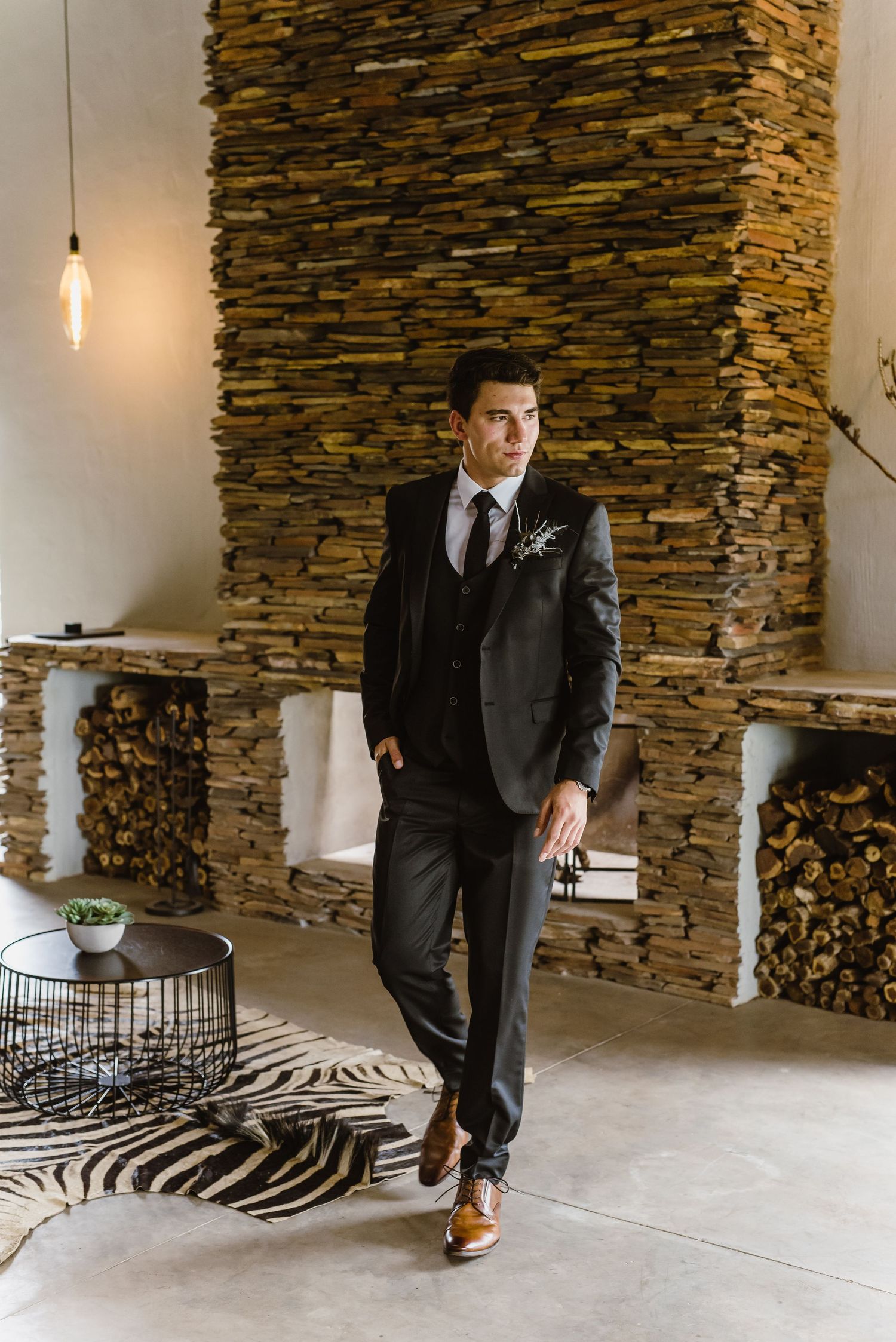 Elegant black suit against textured stone wall in modern indoor setting.