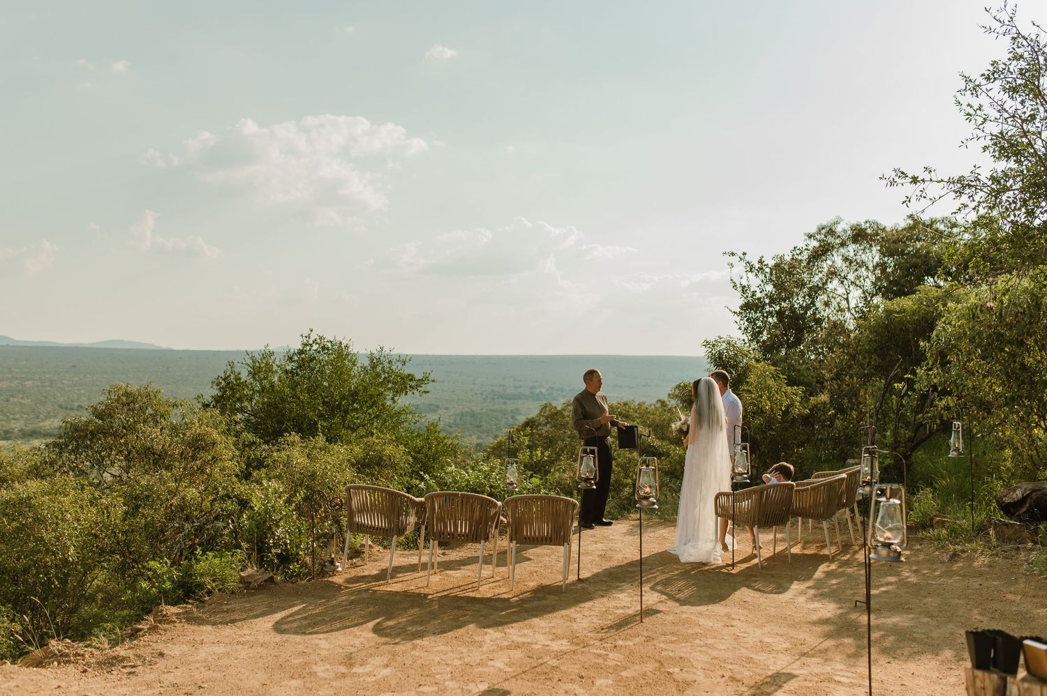 Couple standing at an outdoor bush wedding ceremony with panoramic savanna landscape views.