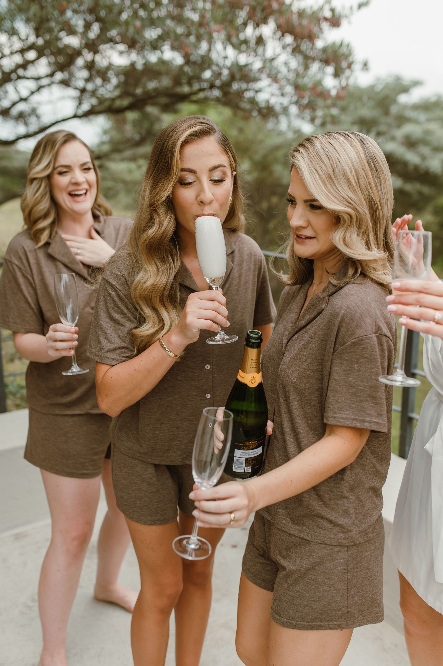 A group in brown shirts laughing and toasting with champagne flutes during a celebration.