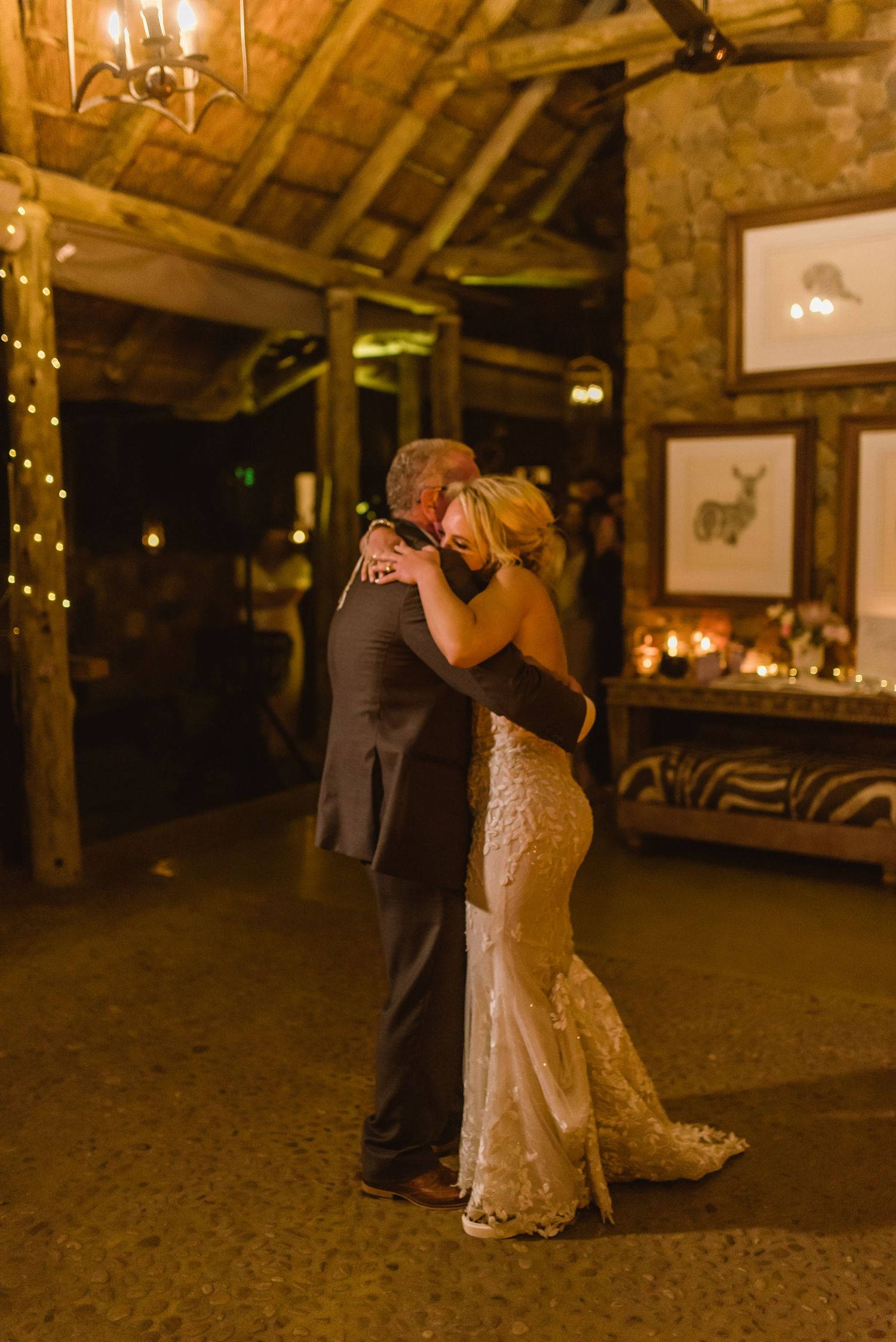 Wedding couples sharing romantic dances on rustic barn dance floor with ambient lighting.