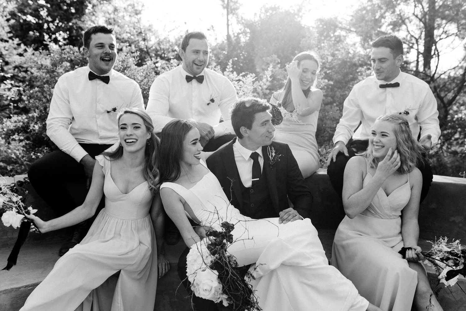 Wedding party relaxing and laughing together on outdoor seating.