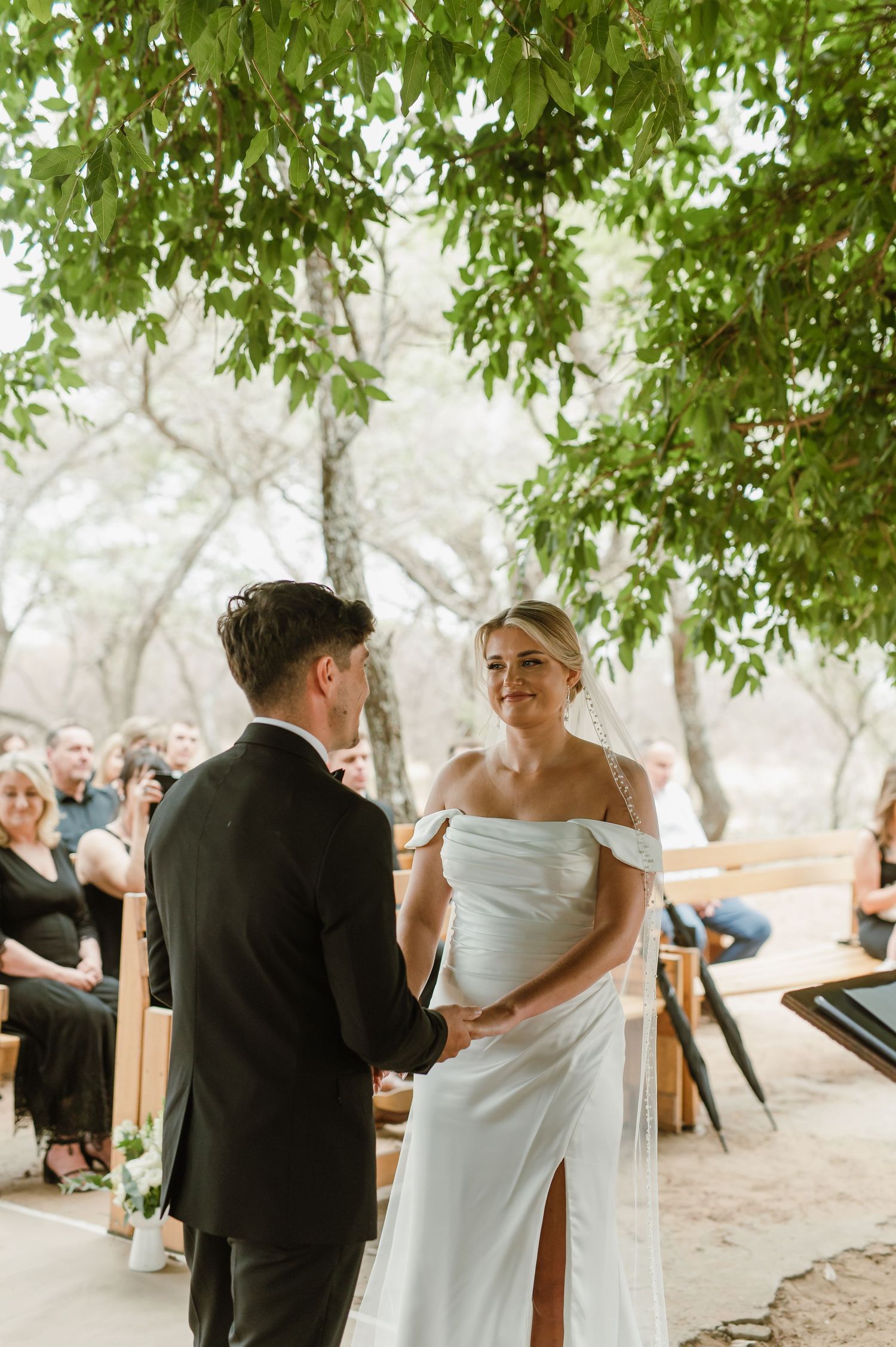 Couple exchanging vows during woodland wedding ceremony with natural backdrop.