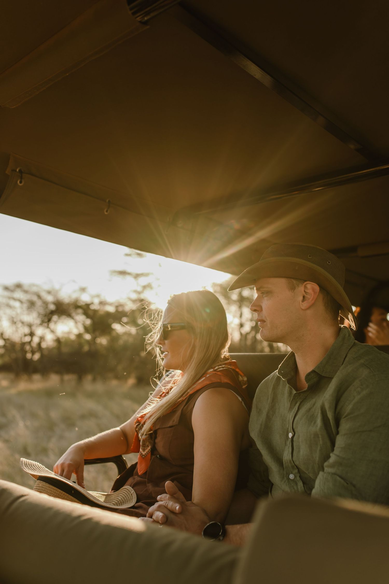 Safari vehicle interior silhouetted against golden African sunset.