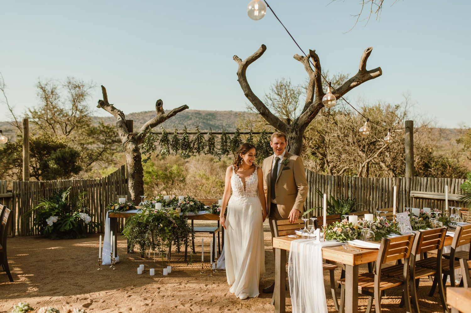 Wedding celebration setup in a desert garden with wooden furniture and string lighting.