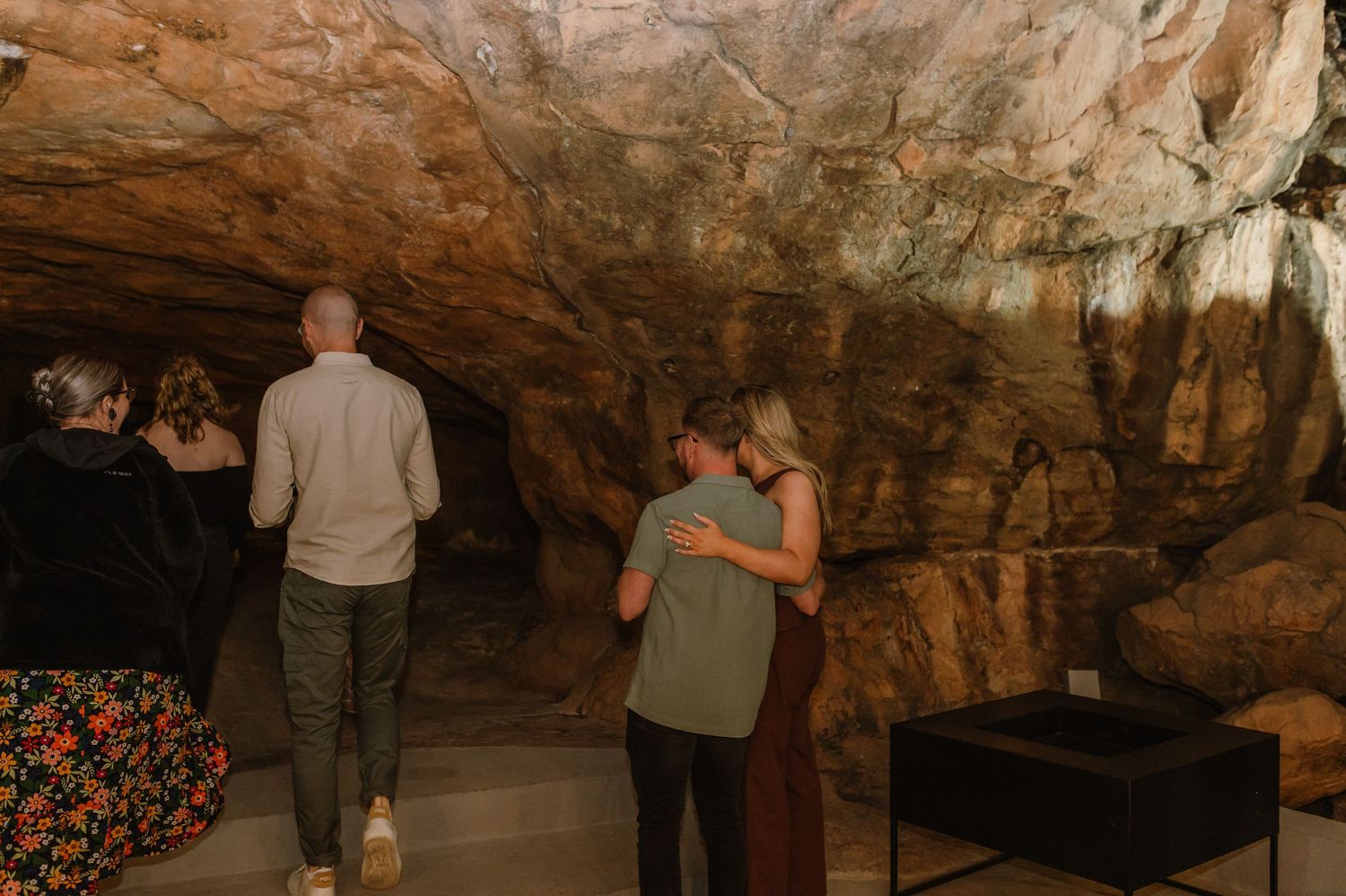 Couples enjoying an intimate moment in a rustic cave setting.
