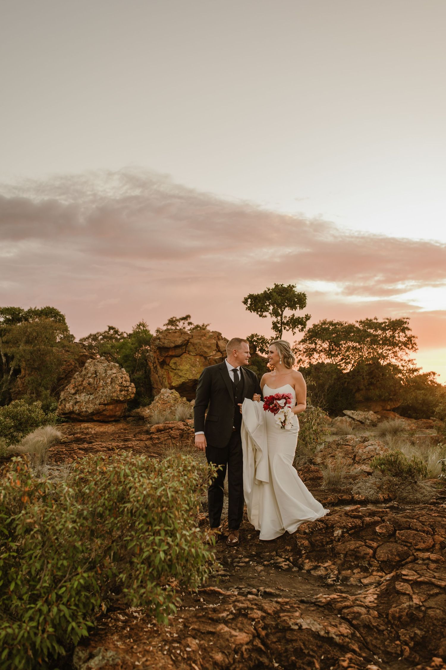 Romantic sunset wedding photos of a couple walking through rugged Australian landscape.