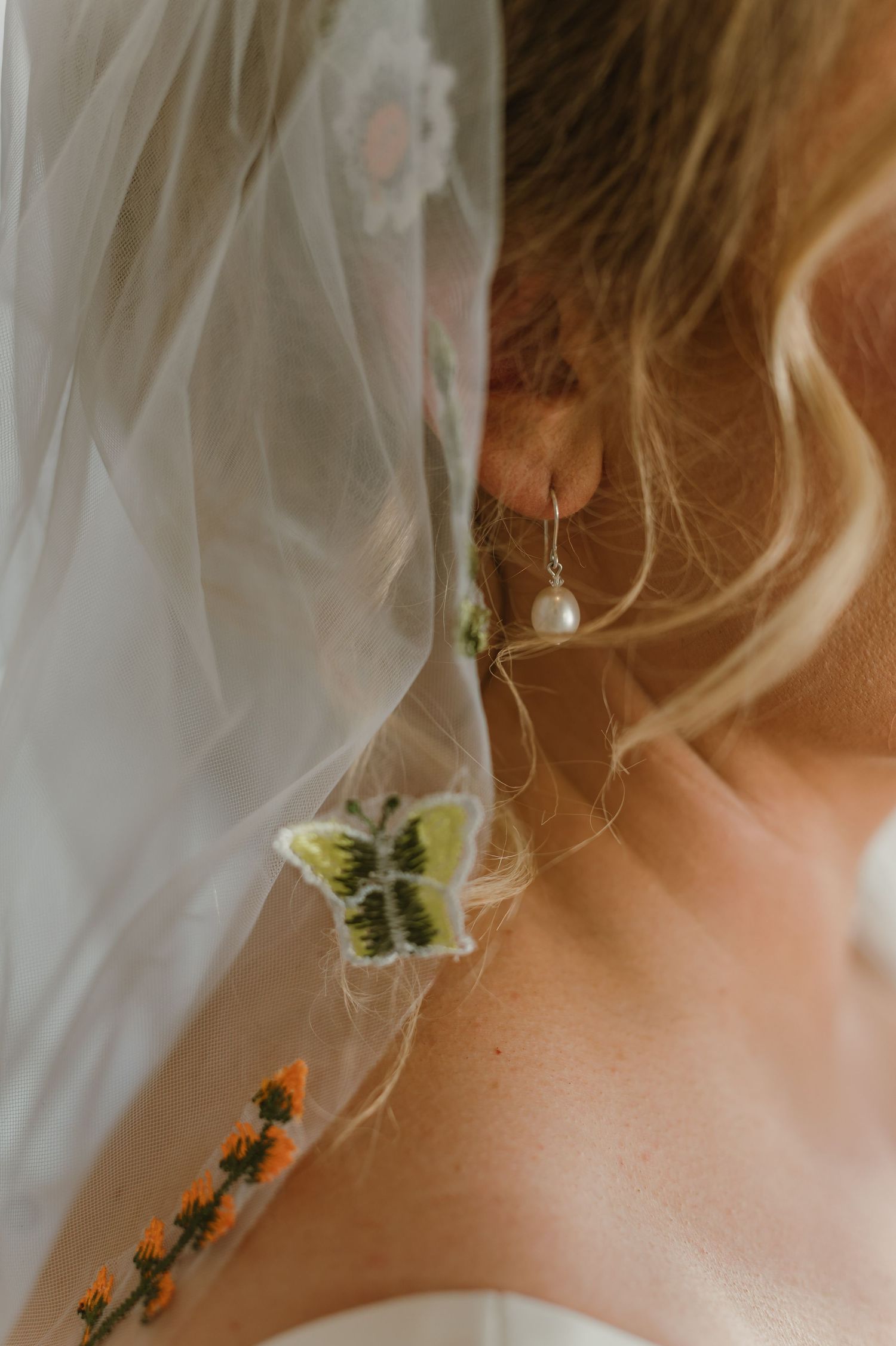 Close-up detail of delicate floral earrings with a white veil in soft focus.
