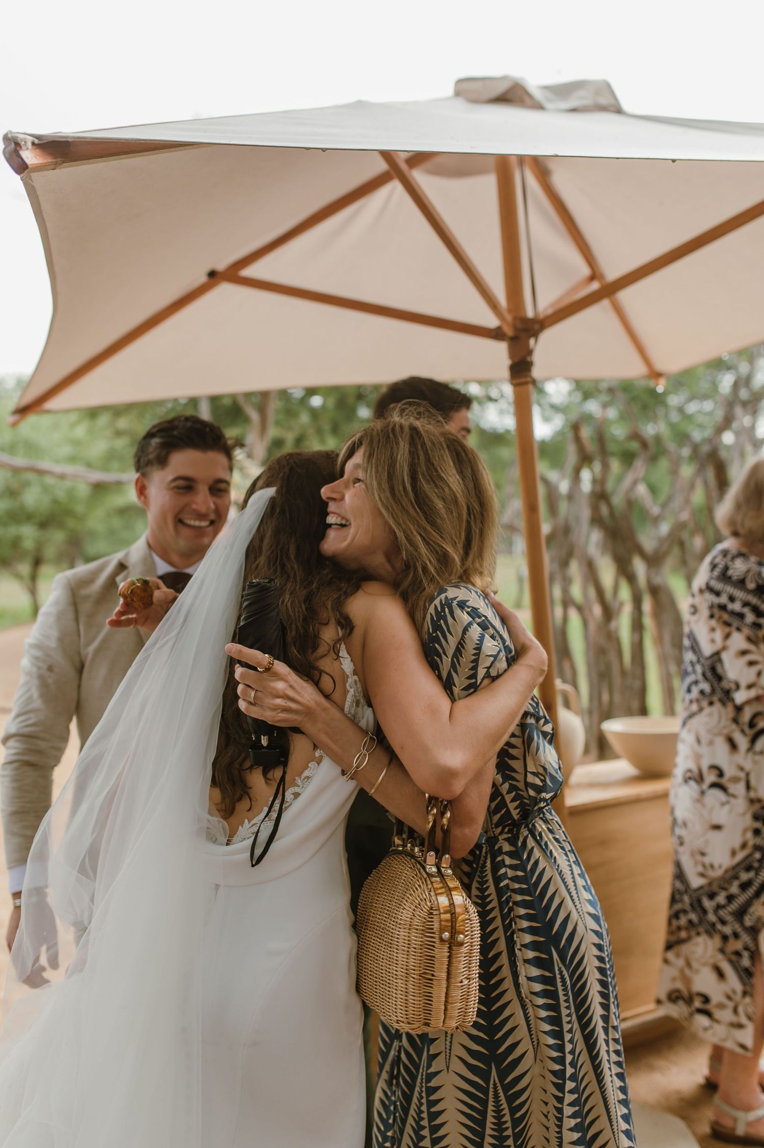 Wedding celebration moments captured under a white umbrella in an outdoor setting.