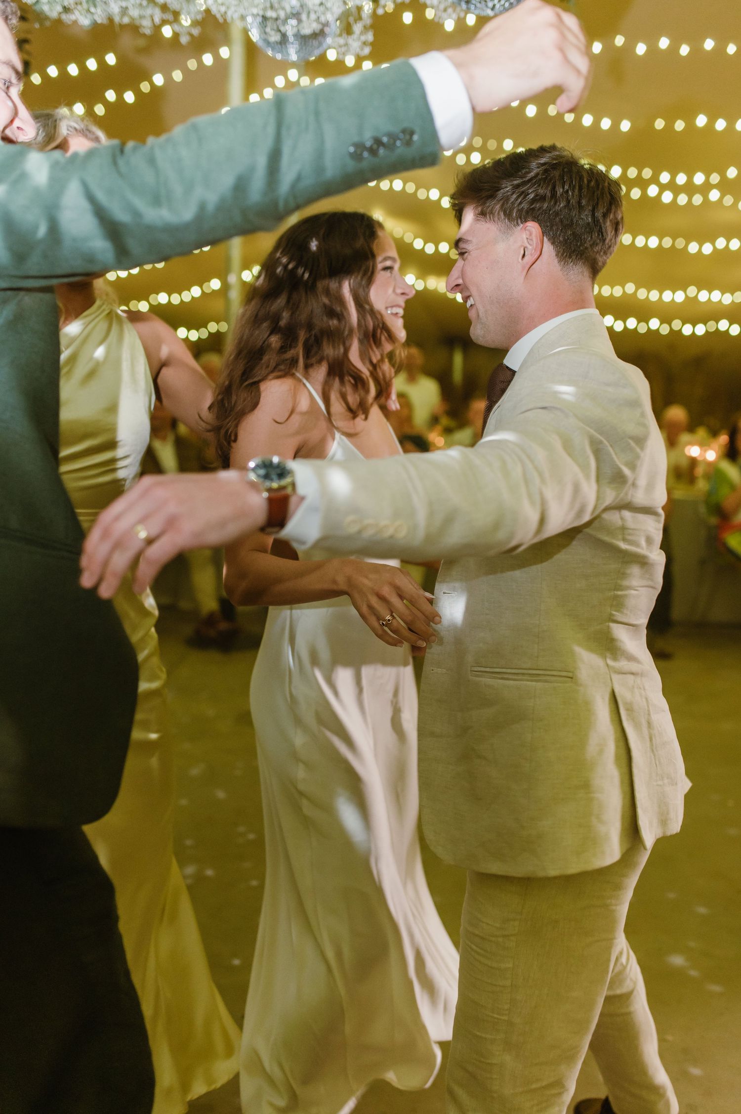 Couples dance in an intimate embrace under romantic tent lighting at a wedding reception.
