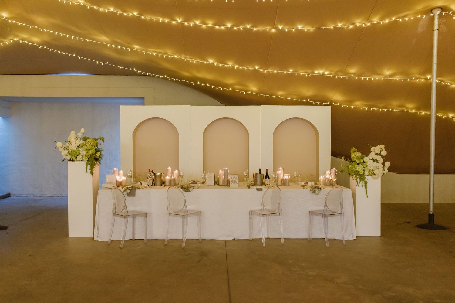 Long banquet tables set under glowing string lights at an elegant outdoor wedding reception.