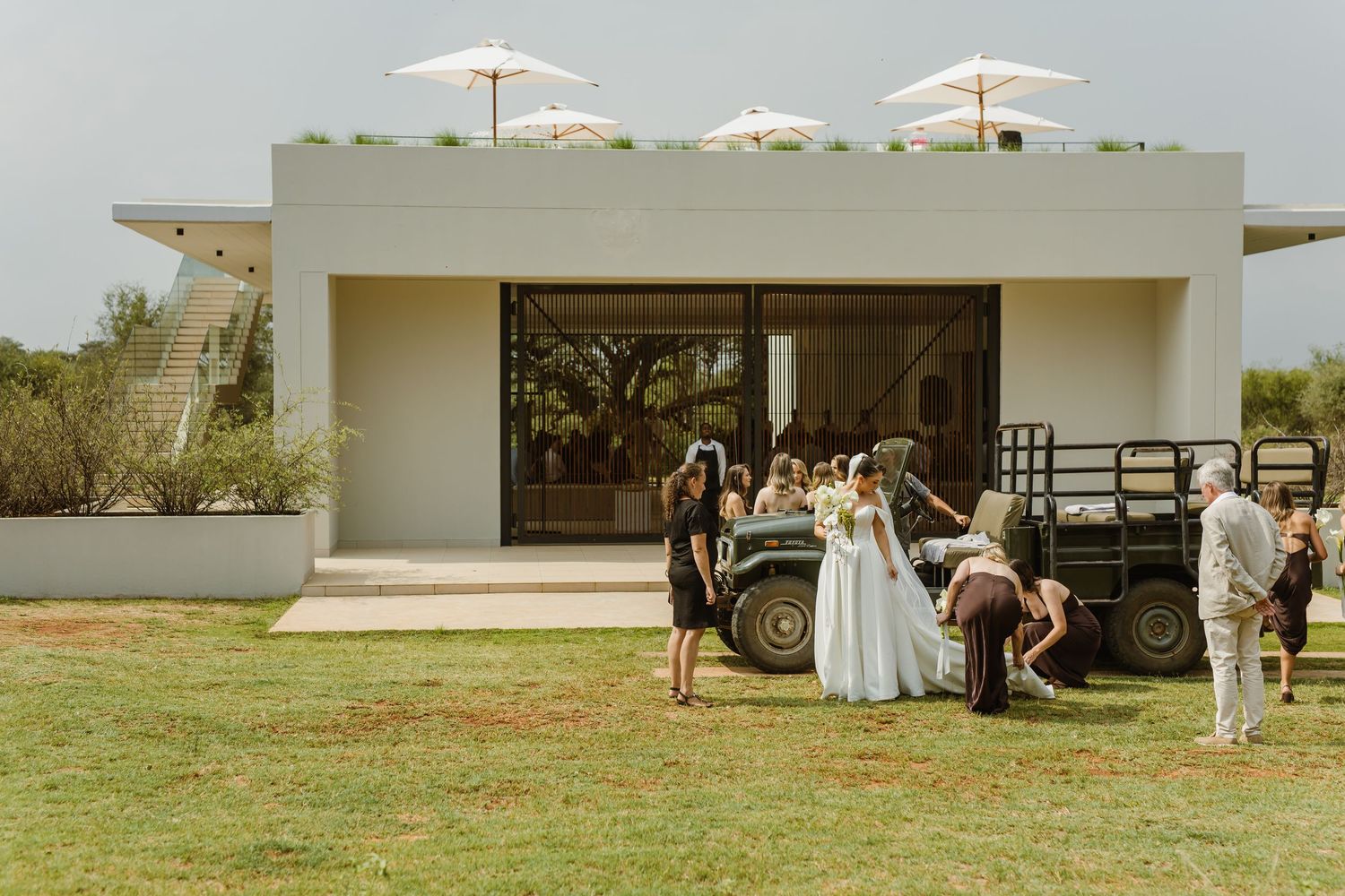 Panoramic view of a modern white venue with outdoor seating and umbrellas on a sunny day.
