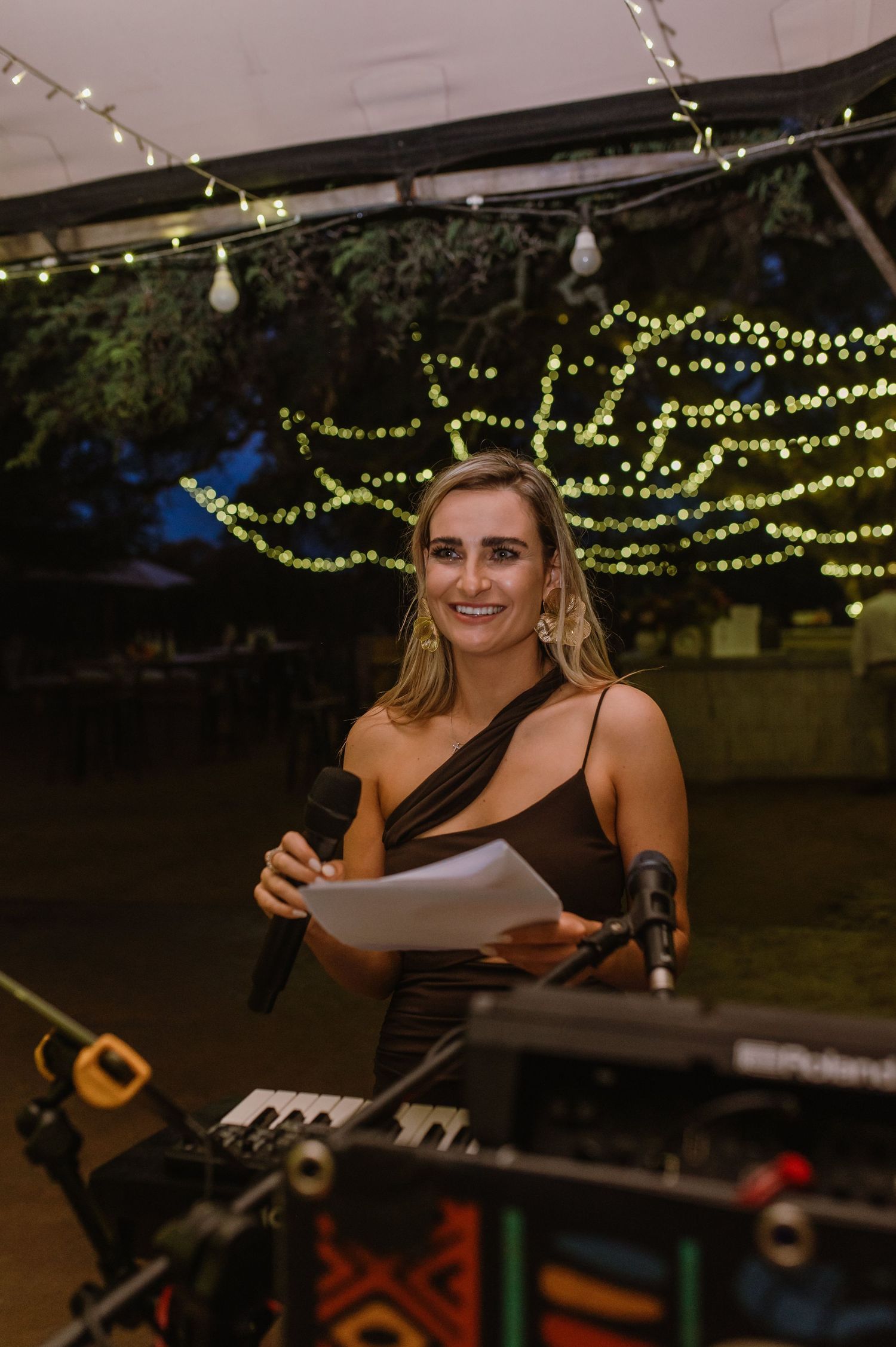 Musician performs under string lights at an outdoor evening event.