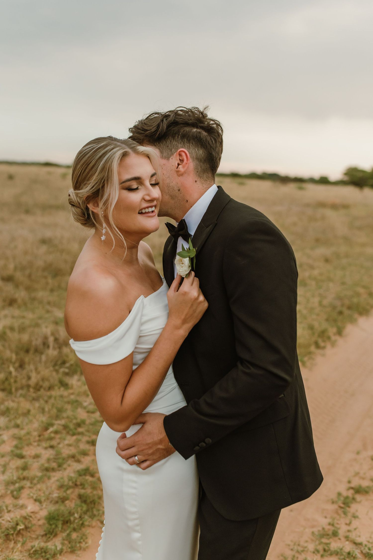 Romantic wedding portraits captured on a rustic country path during golden hour.