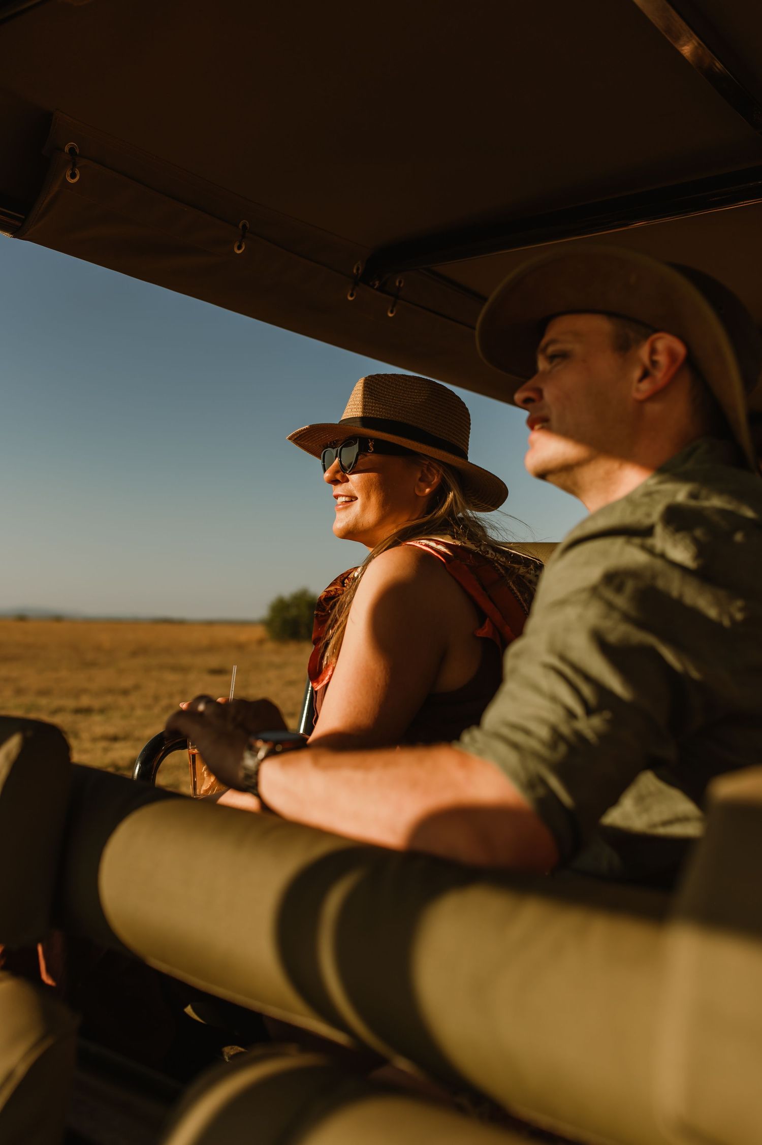 Safari-goers enjoy the golden hour view from their vehicle in the African wilderness.