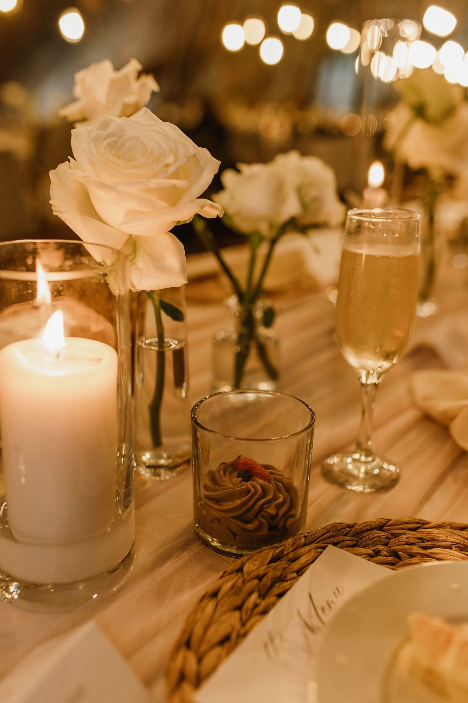 Elegant table setting with white roses, candles, and glowing ambient lighting creates a romantic atmosphere.