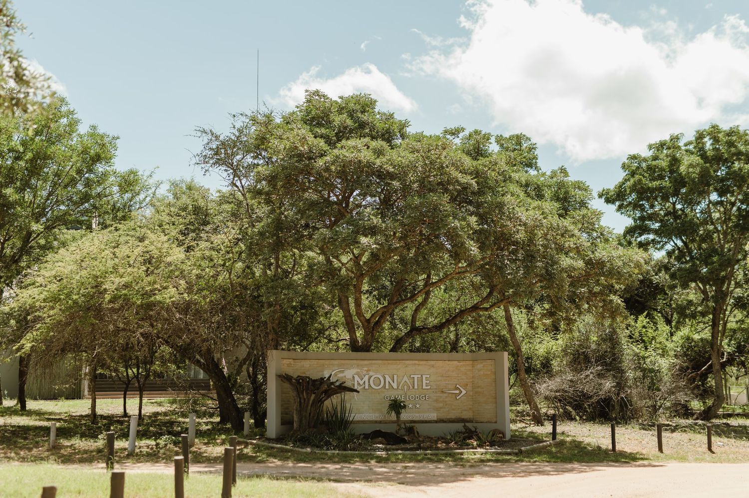 Lodge entrance sign surrounded by lush green trees and vegetation.