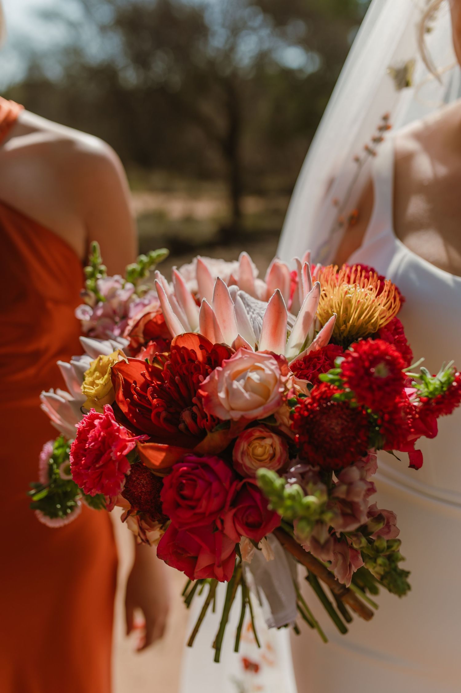 Close-up of red and burgundy wedding bouquets with roses and mixed flowers.