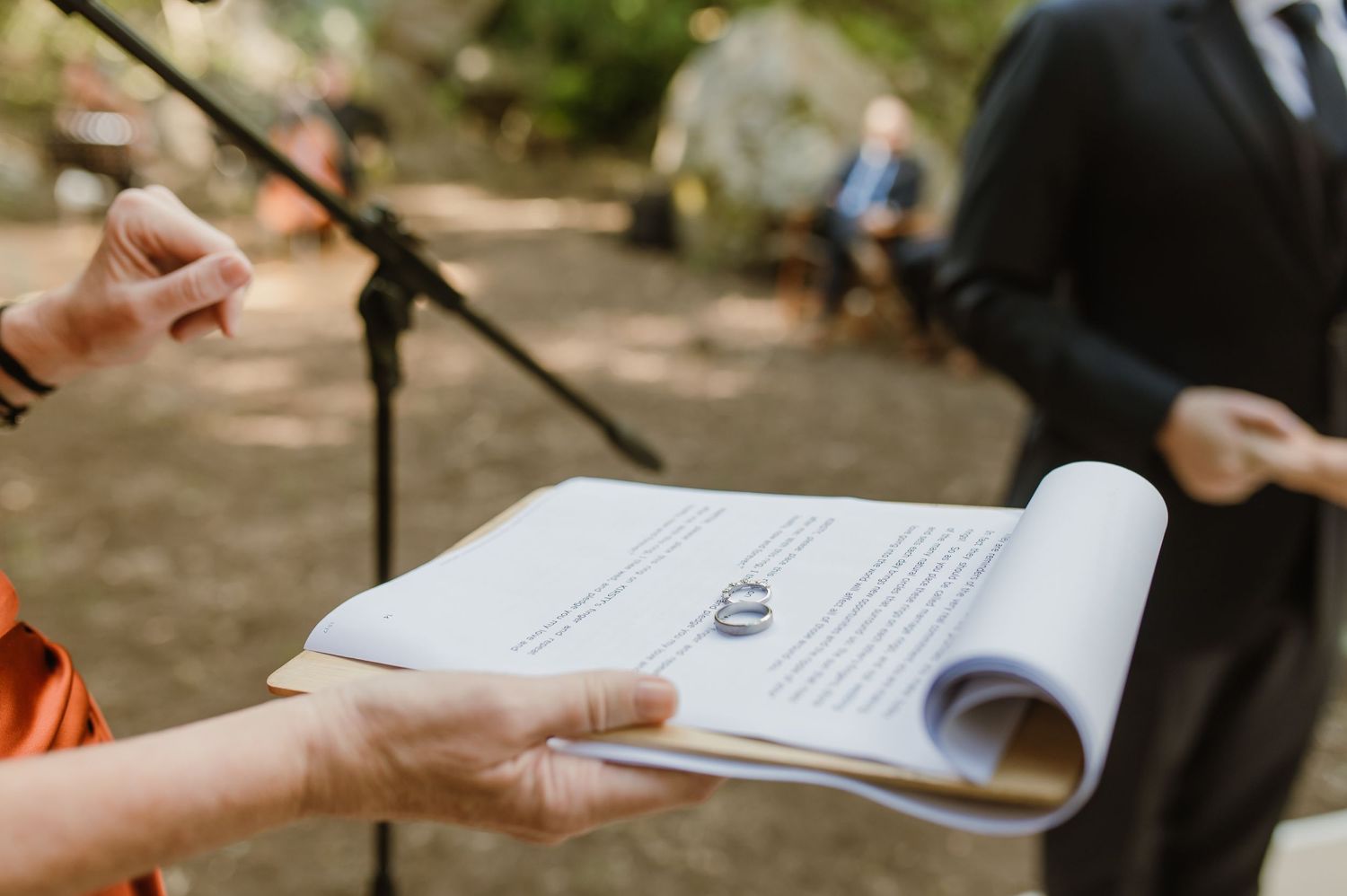 Close-up of wedding ceremony readings and vows being exchanged in a woodland setting.