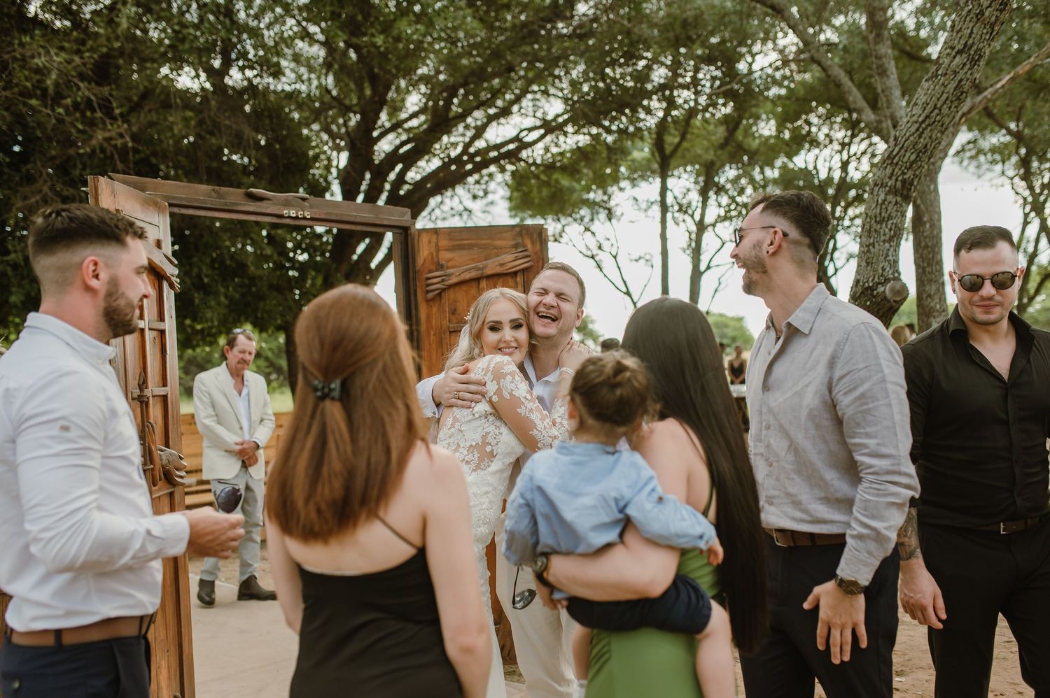 Casual wedding reception with guests mingling under tree canopy.
