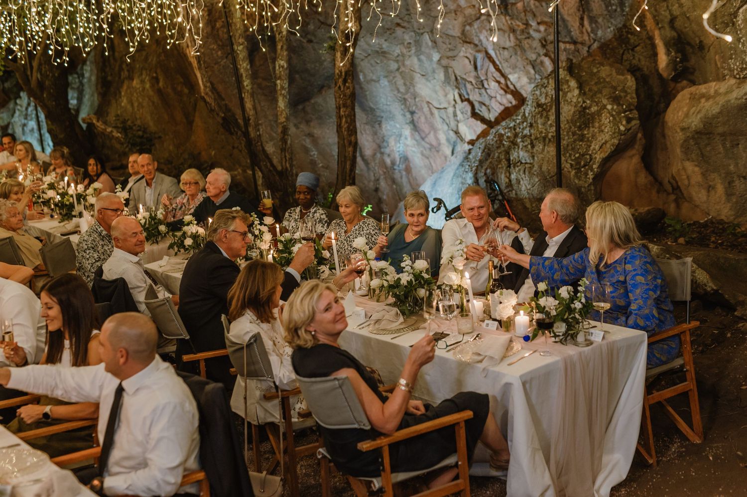 Wedding reception dinner setup with long tables and atmospheric lighting in a cave-like venue.