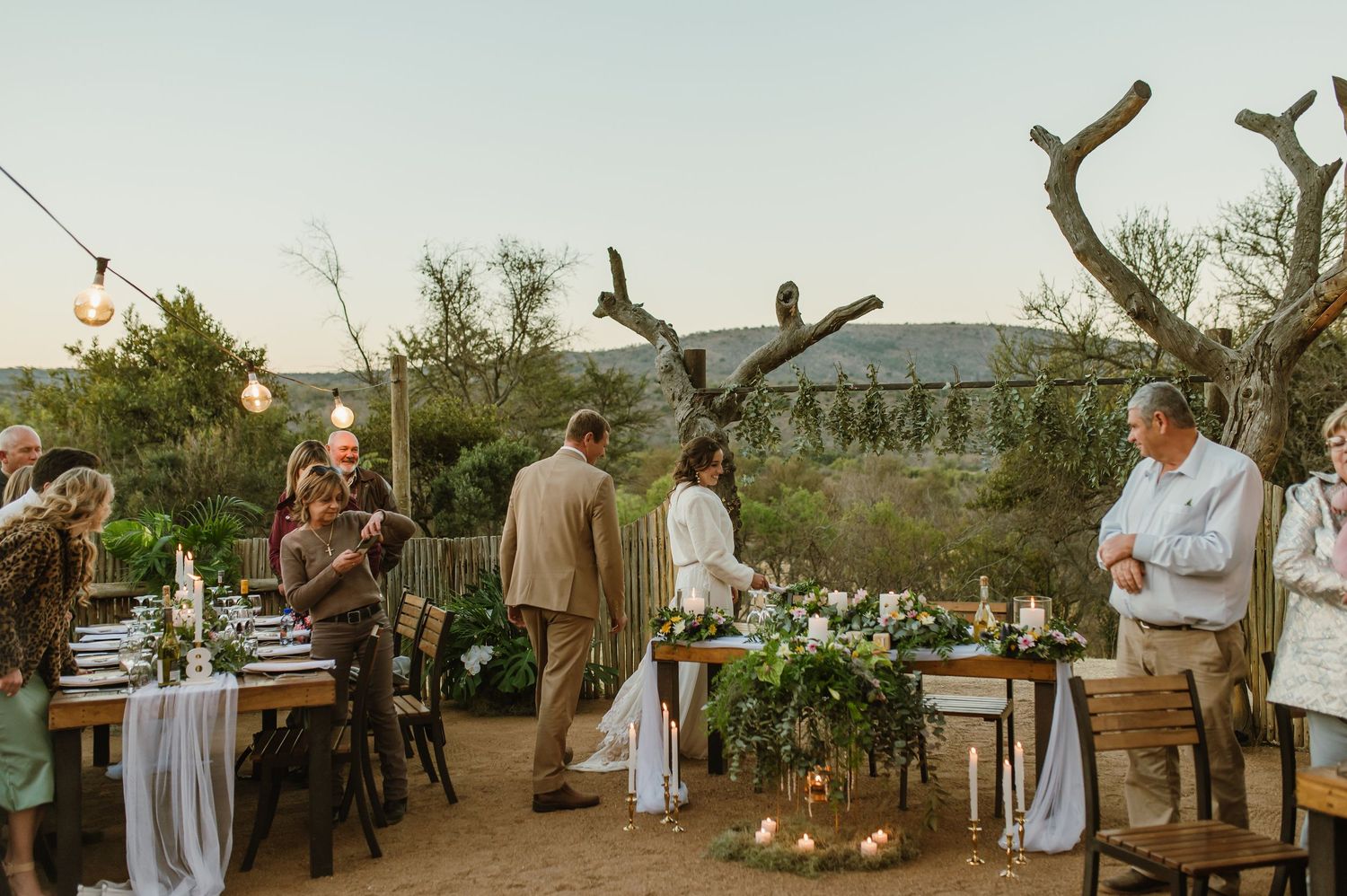 Outdoor wedding reception area with string lights, white drapes and rustic wooden details.