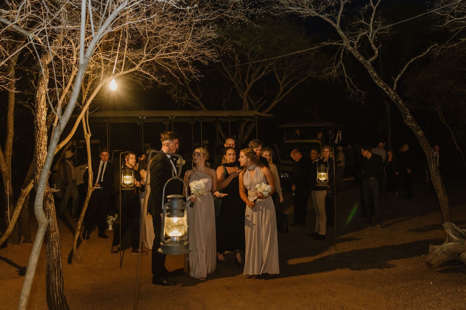 Evening outdoor gathering with lanterns illuminating a natural wooded setting.