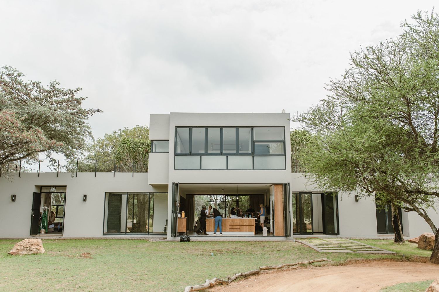 Modern white wedding venue with floor-to-ceiling windows and minimalist architecture set against a natural landscape.