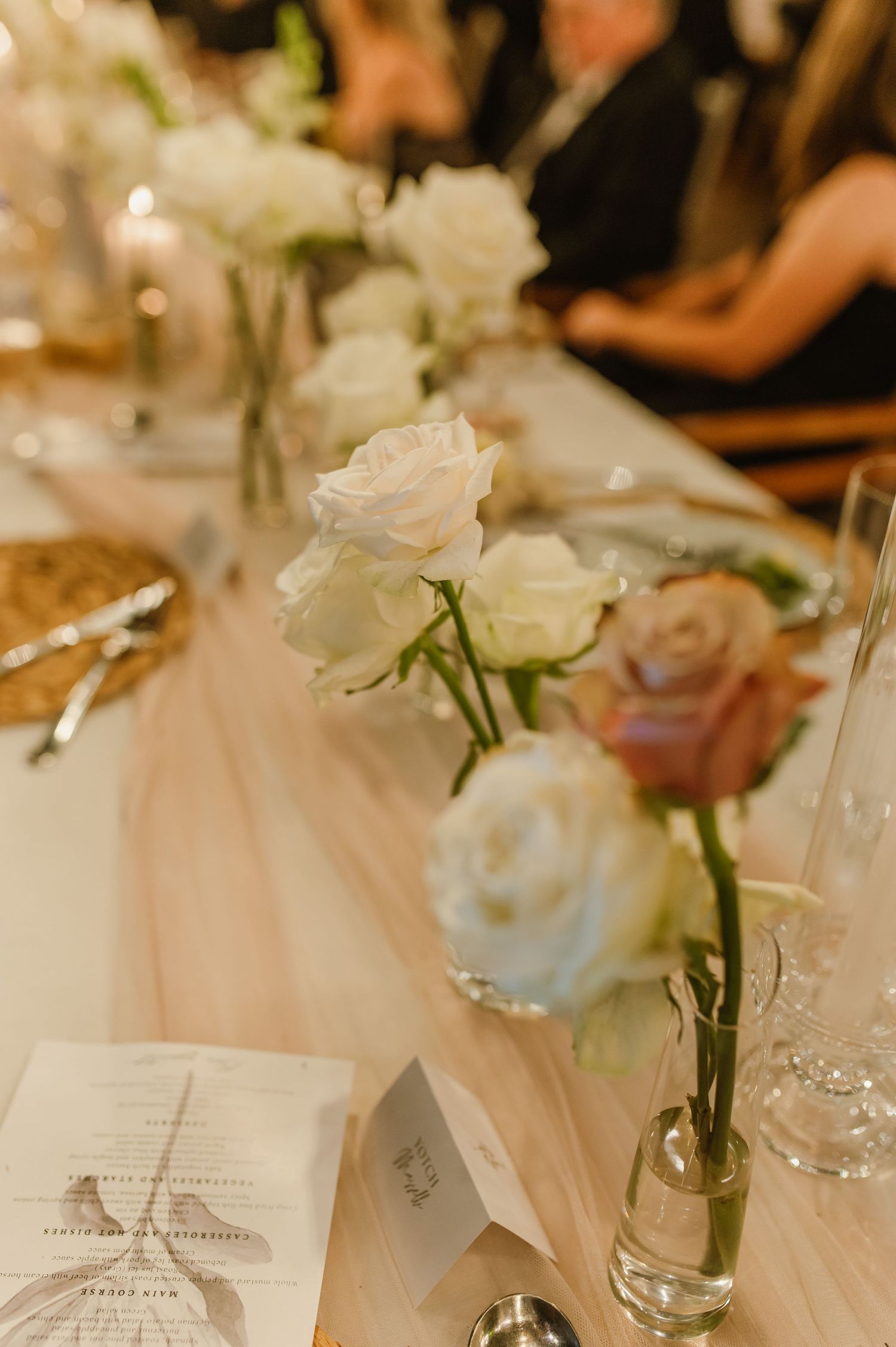 White floral centerpieces and place settings on elegant wedding reception tables.