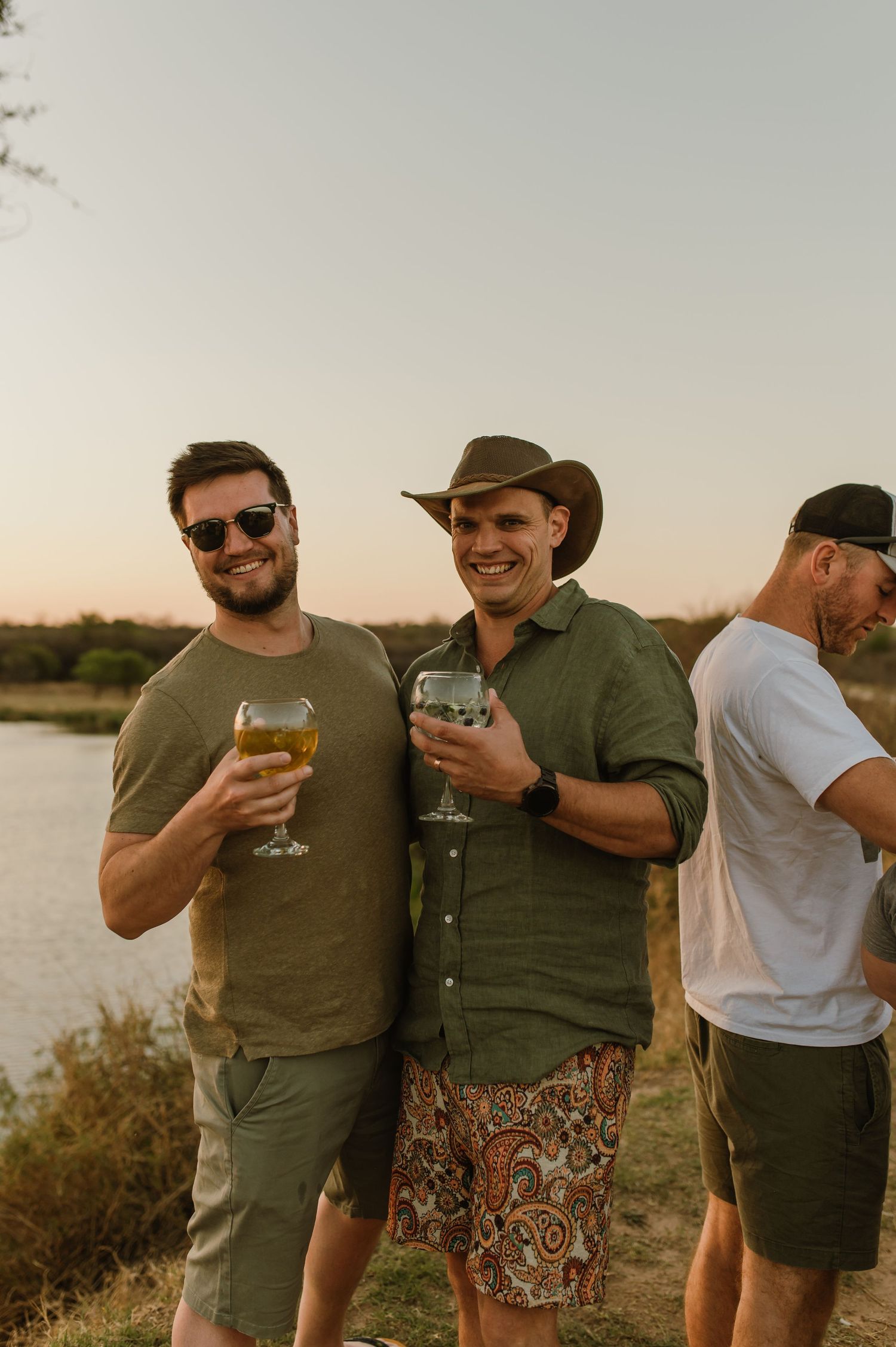 Friends enjoying drinks during outdoor safari sundowner experience at sunset.