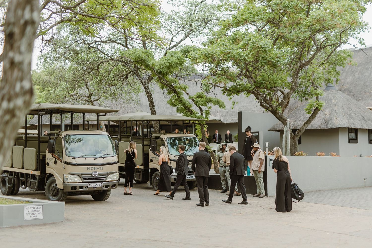 Wedding guests boarding safari vehicles at an outdoor venue.