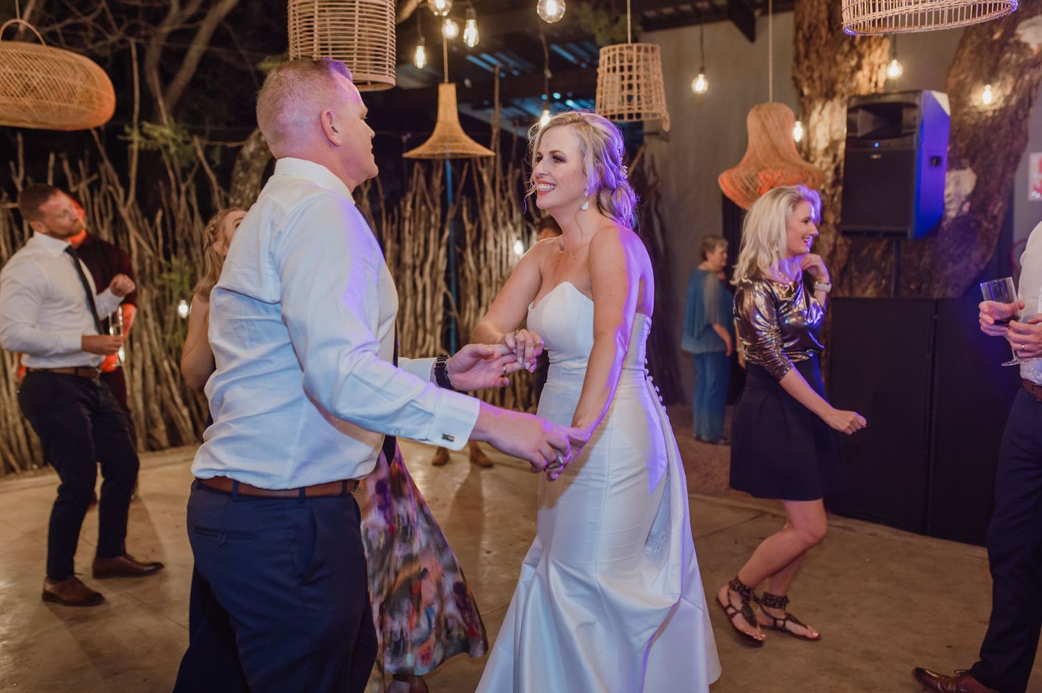 Lively dance floor moment captured at outdoor wedding with hanging lantern decorations.