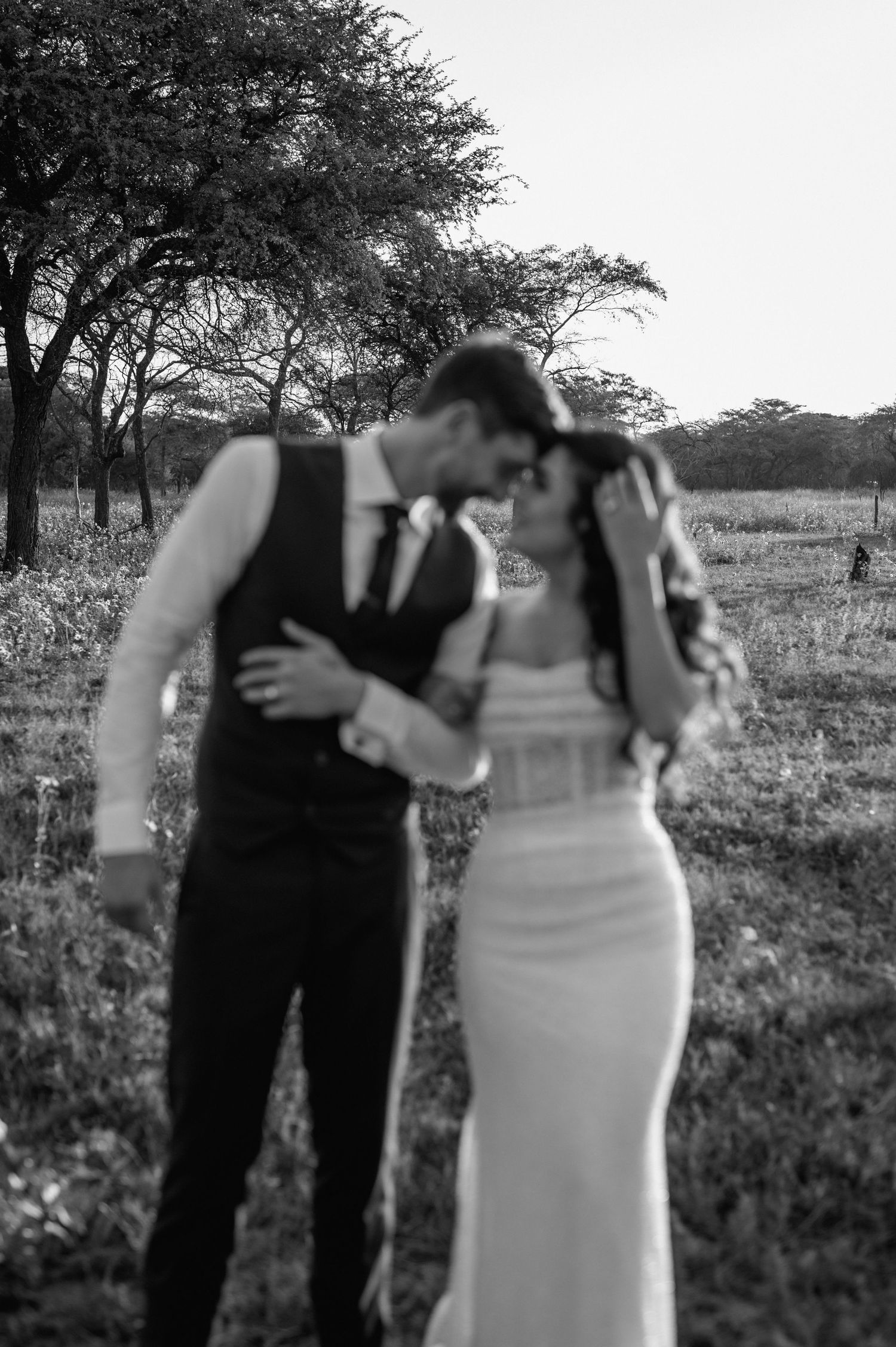 An intimate black and white portrait of a couple in formal attire outdoors.