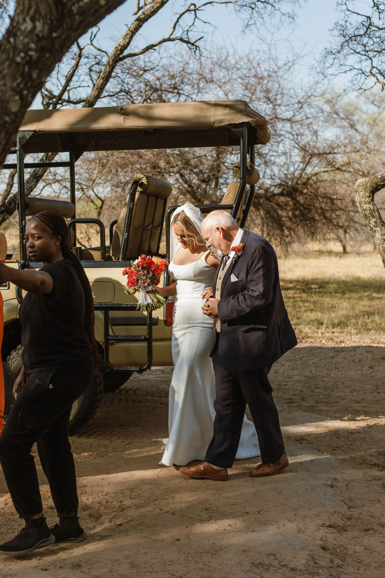 A couple dances together during a romantic outdoor wedding ceremony under a rustic canopy.