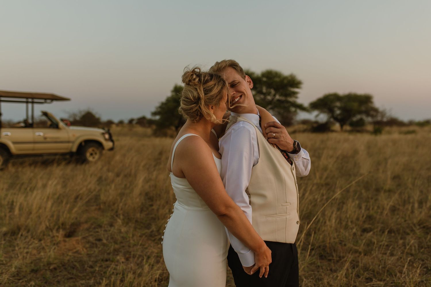 Couple embracing during sunset photoshoot in a rustic outdoor setting.