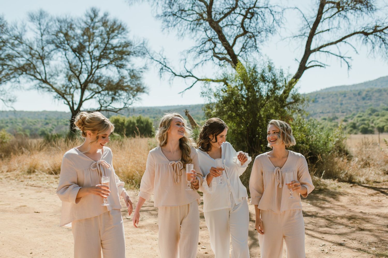 Several people in light colored outfits share joyful moments outdoors against a natural desert landscape.