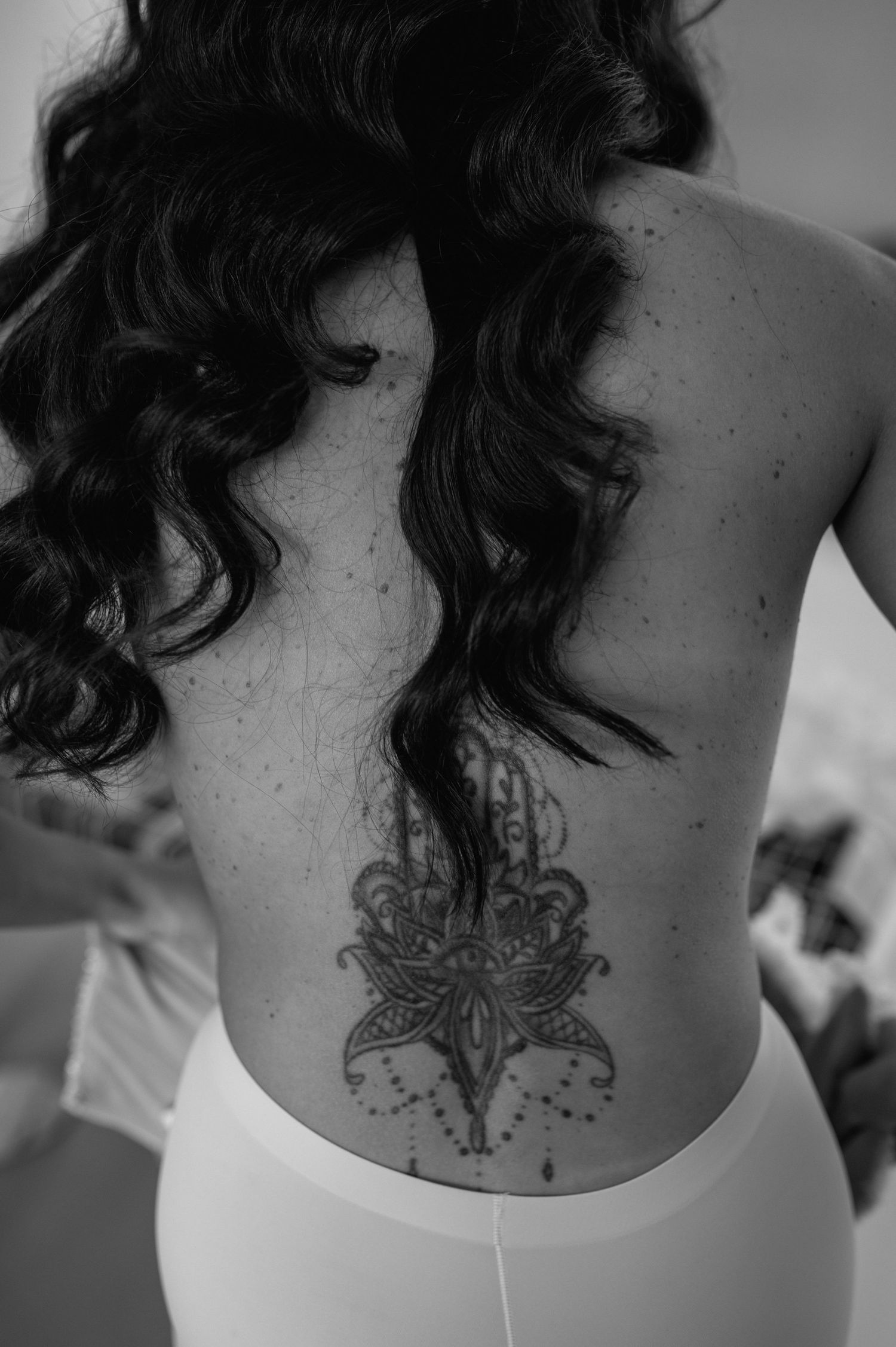 Black and white close-up of an intricate butterfly tattoo design on someone's back.