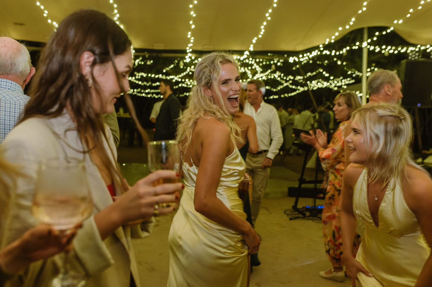 Reception venue decorated with romantic string lights as guests dance and celebrate.