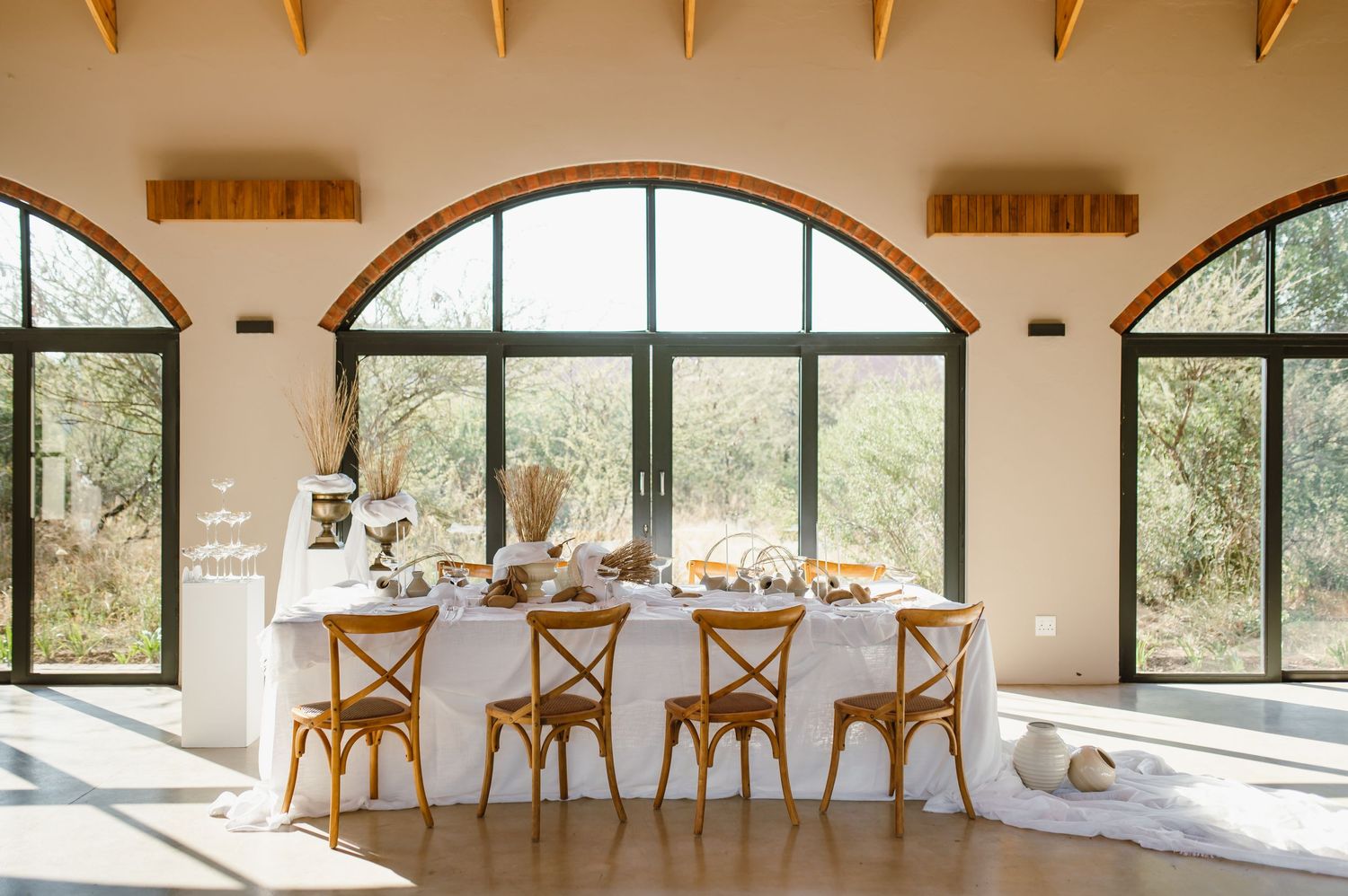 Rustic event venue with wooden beamed ceiling and arched windows overlooking natural scenery.