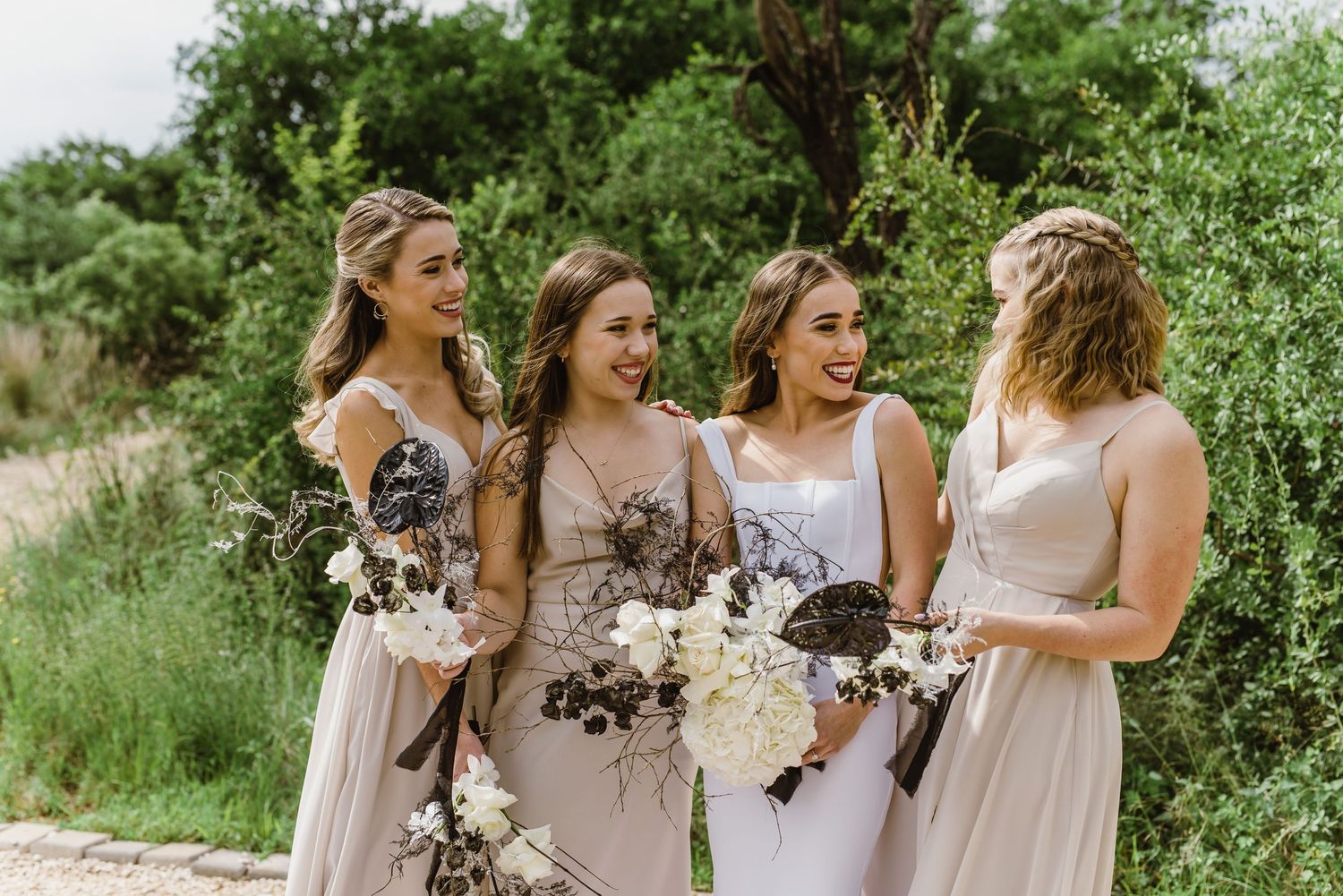 Bridal party walks together holding bouquets on natural outdoor path.