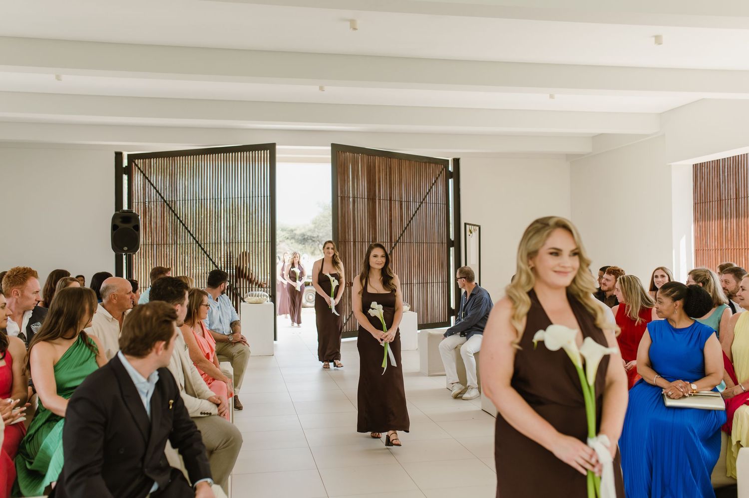 Wedding celebration in a bright minimalist venue with guests dancing and socializing.