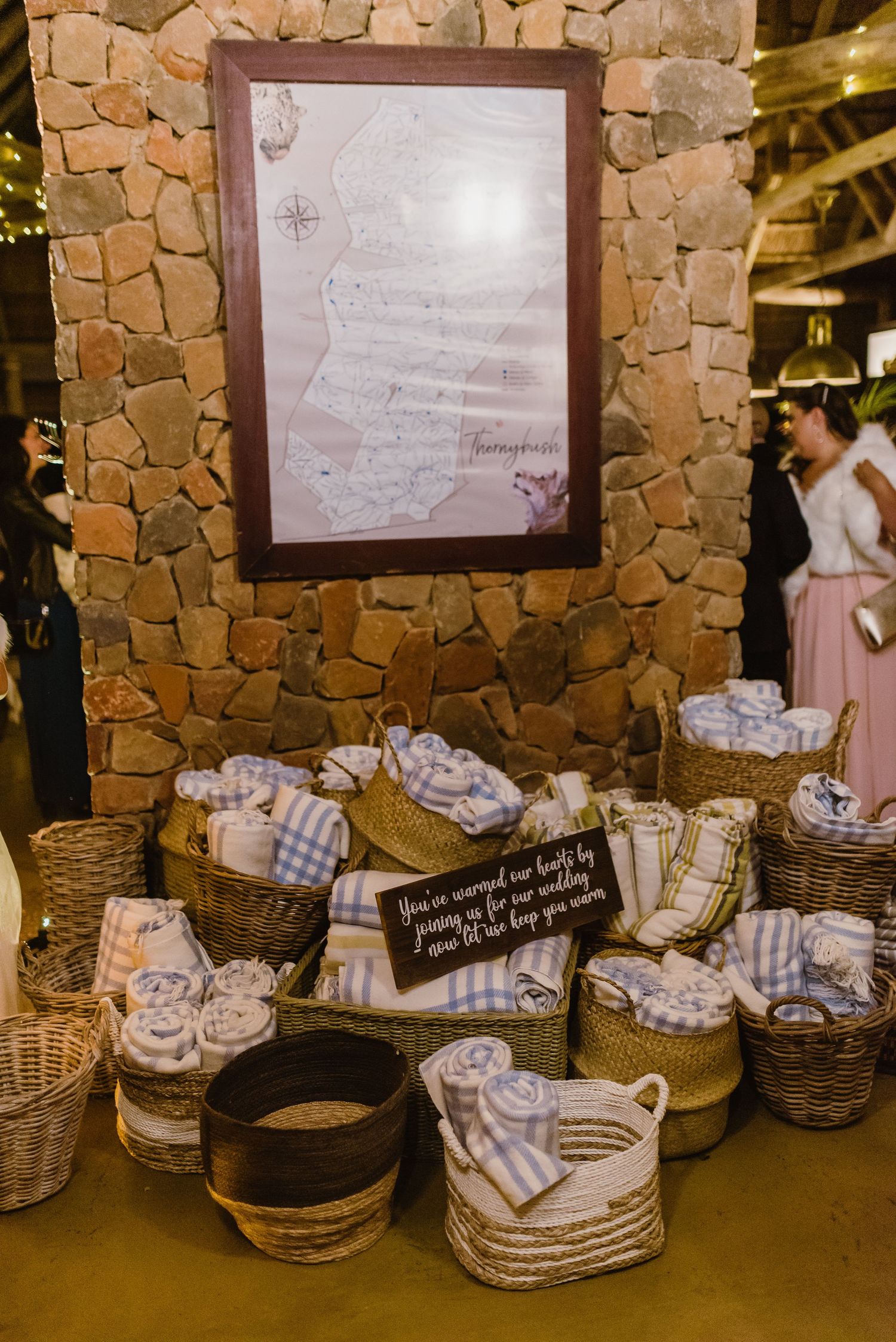 Wedding favor display with woven baskets and blue gingham linens against stone wall.